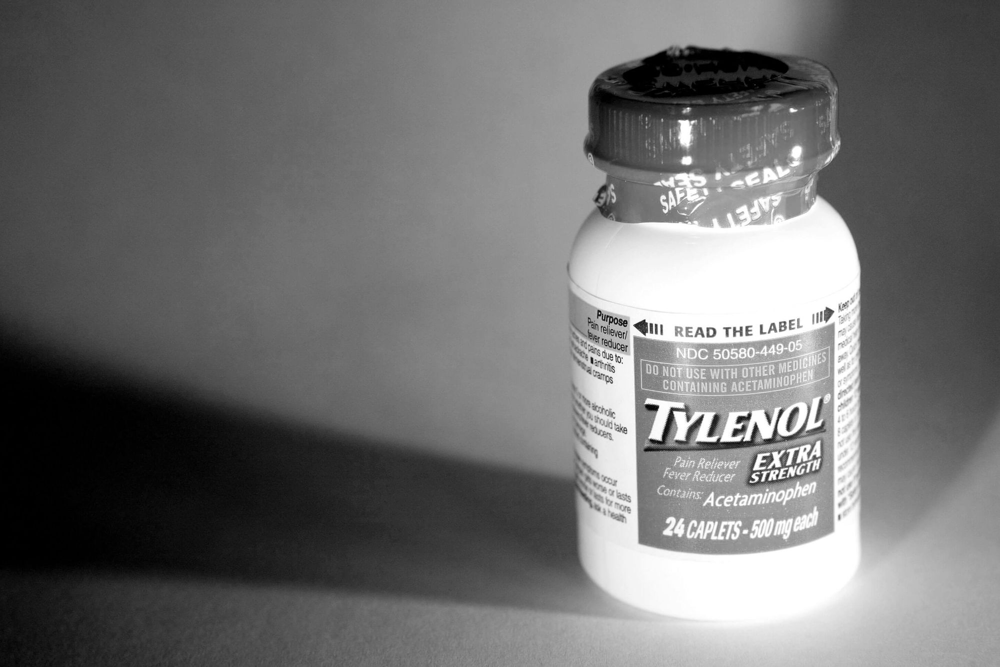 A bottle of Tylenol on a dark background.