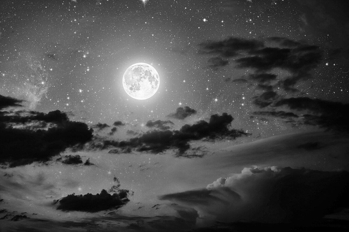 The night sky with stars and moon and clouds.